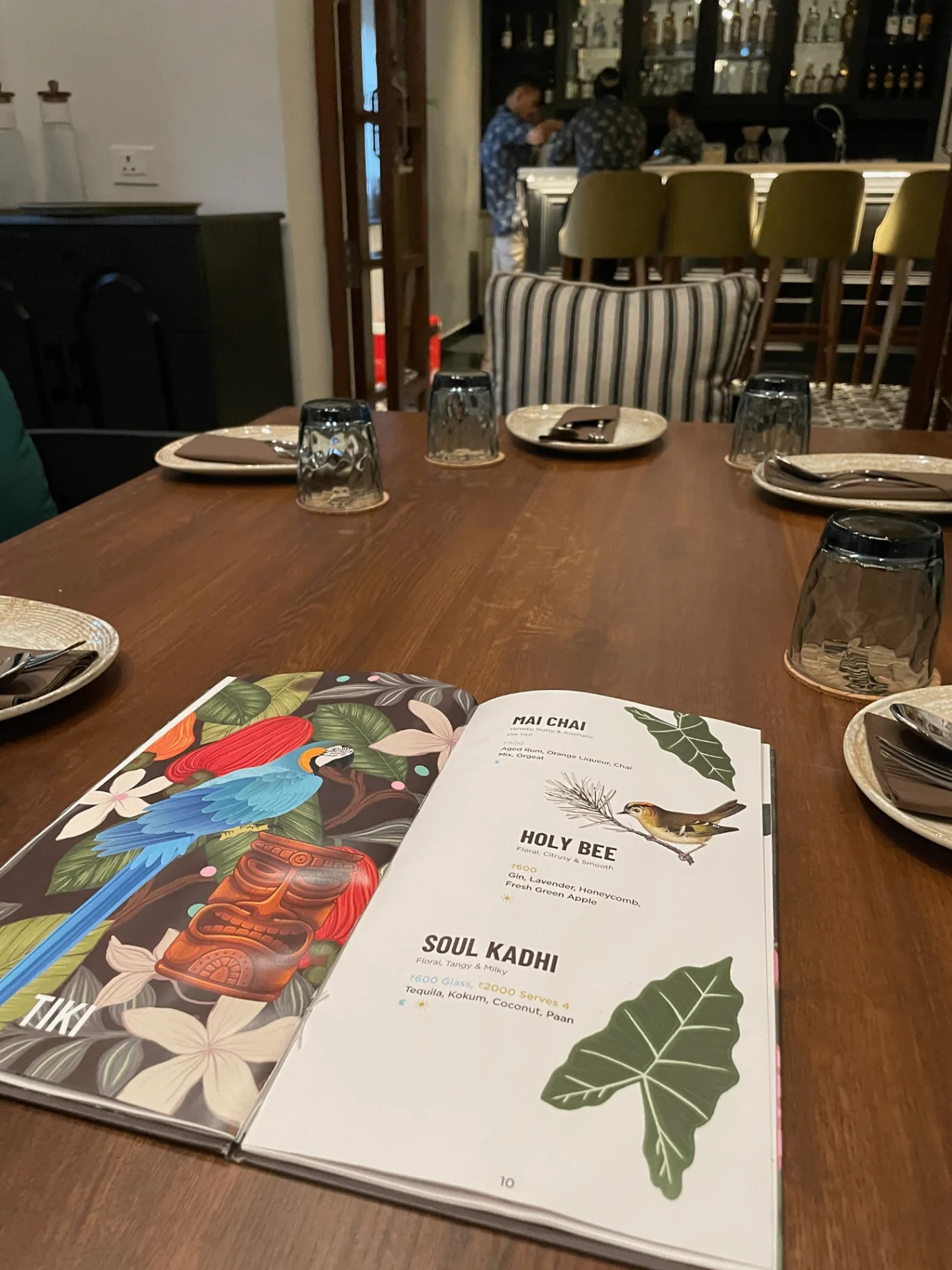 HOSA GOA - Table setting featuring signature cocktails menu with Chai Chai, Holy Bee, and Soul Kadhi