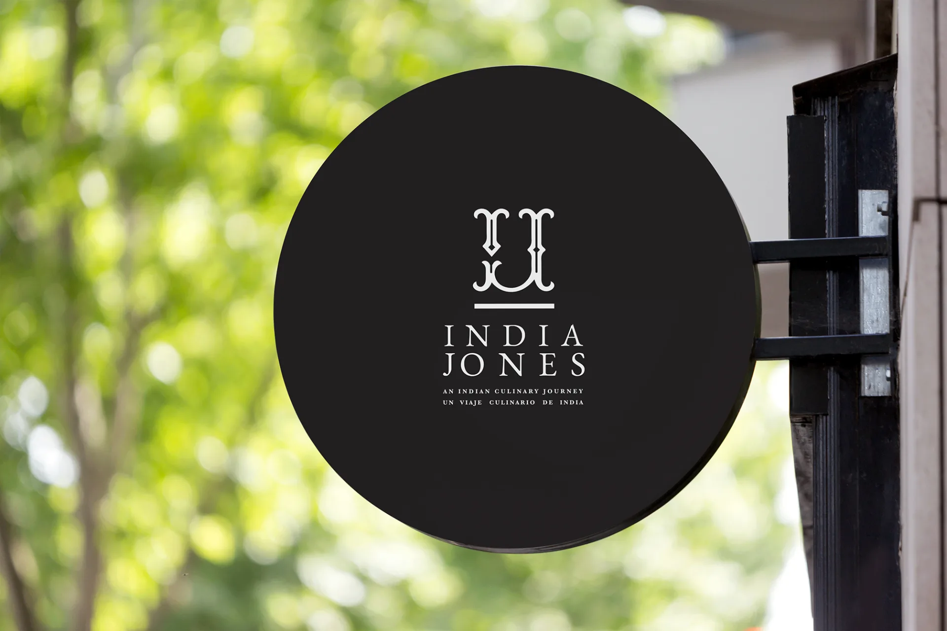 India Jones - Circular restaurant signage with black background and white logo typography