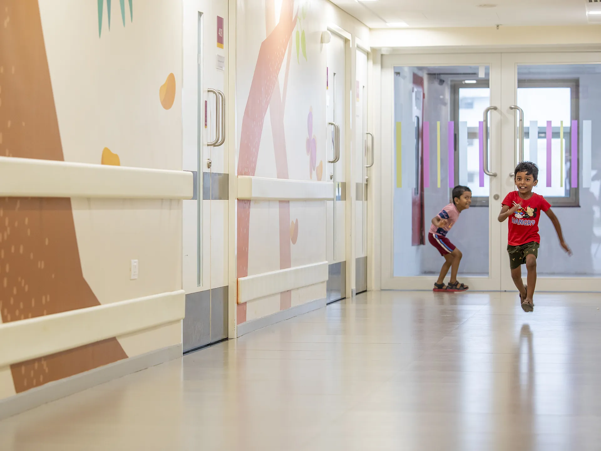 Kauvery Hospital - Children running down a corridor with storybook tree mural